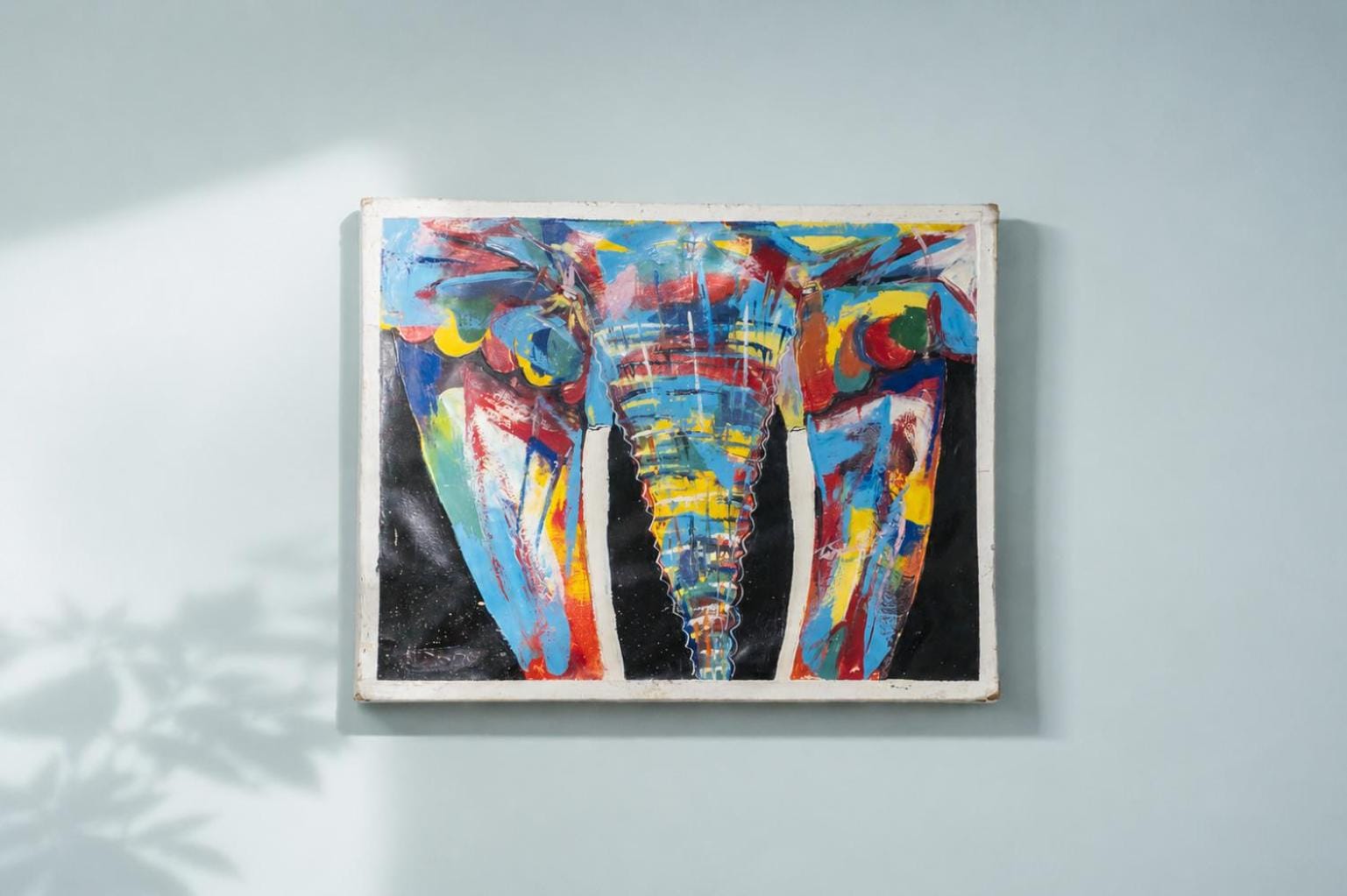 a brightly painted elephant canvas on a pale blue wall