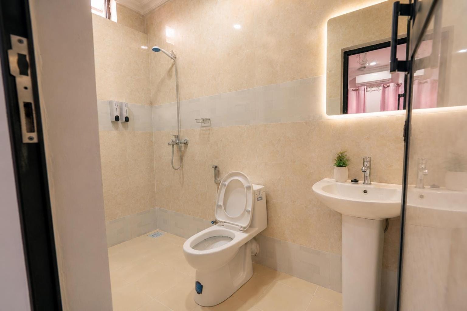 a white tiled bathroom with a shower, basin and mirror