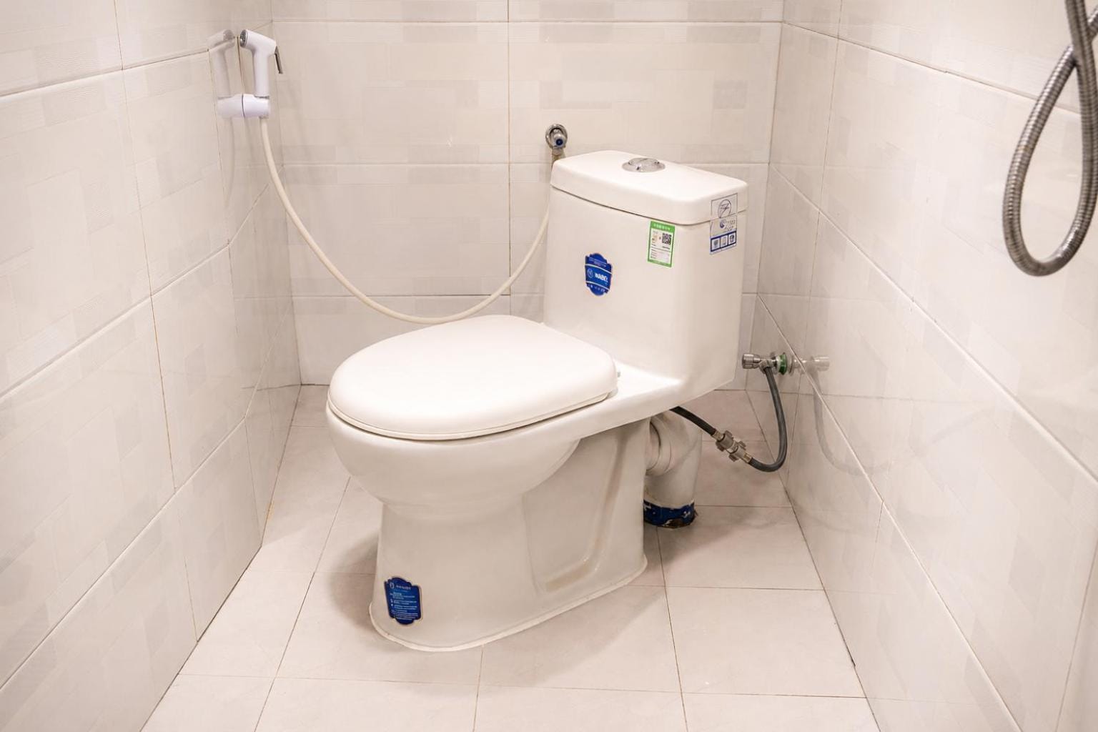 a white tiled bathroom with a shower and toilet