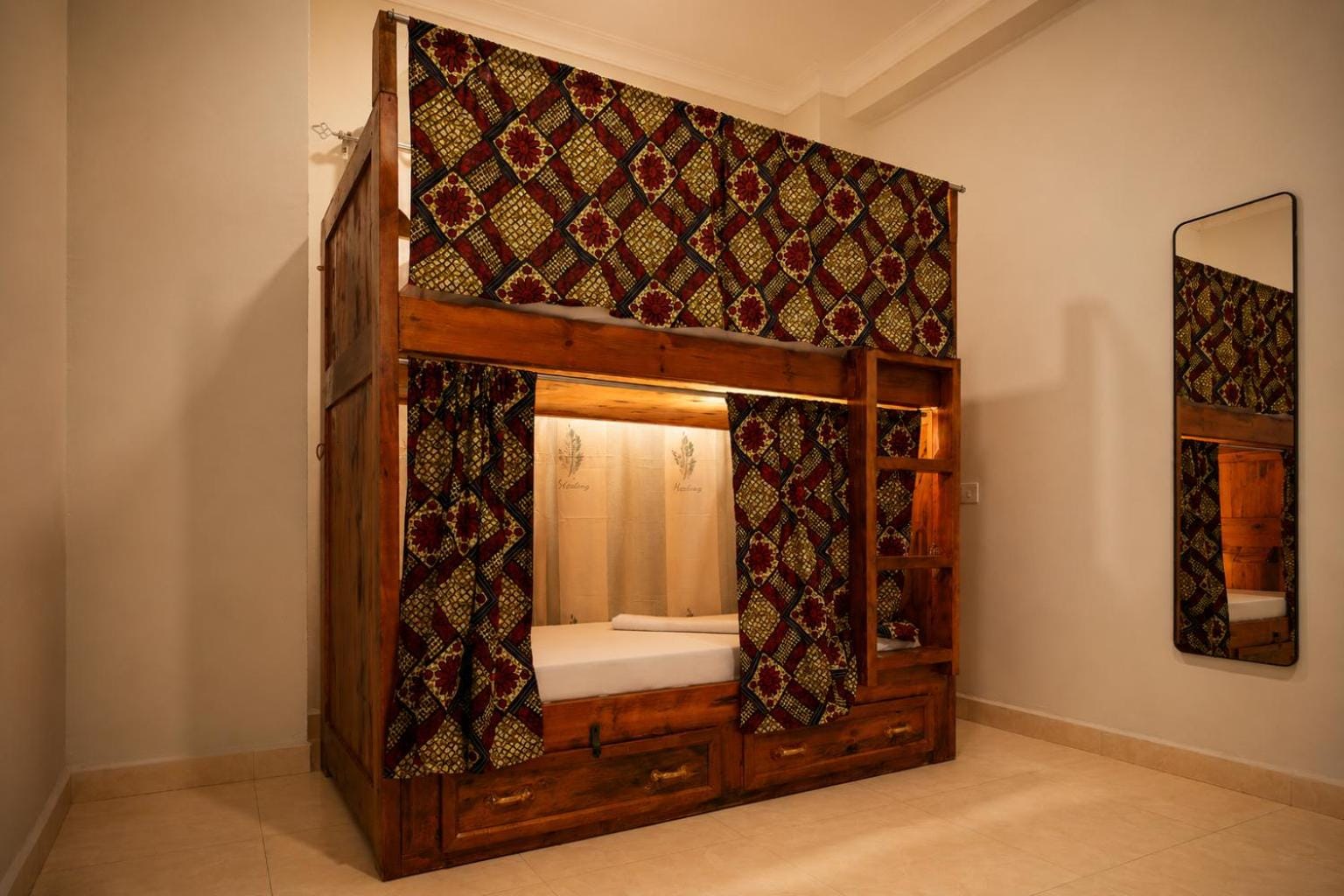 a teak bunk bed with a printed privacy curtain in a whitewashed room