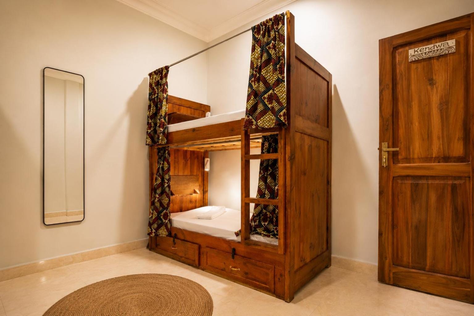 a teak bunk bed beside a tall mirror in a pale room