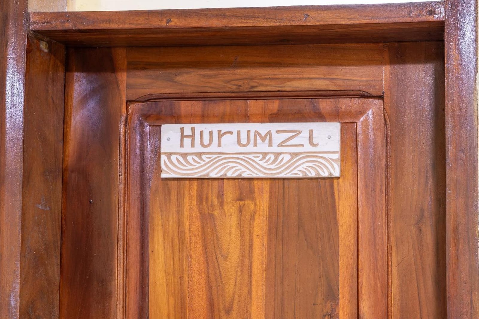 a carved wooden plaque reading Hurumzi on a solid teak door