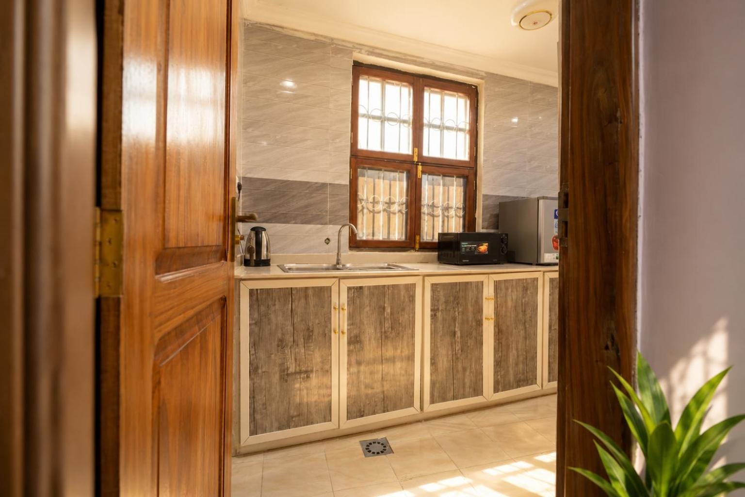a tiled counter run with cupboards and a microwave