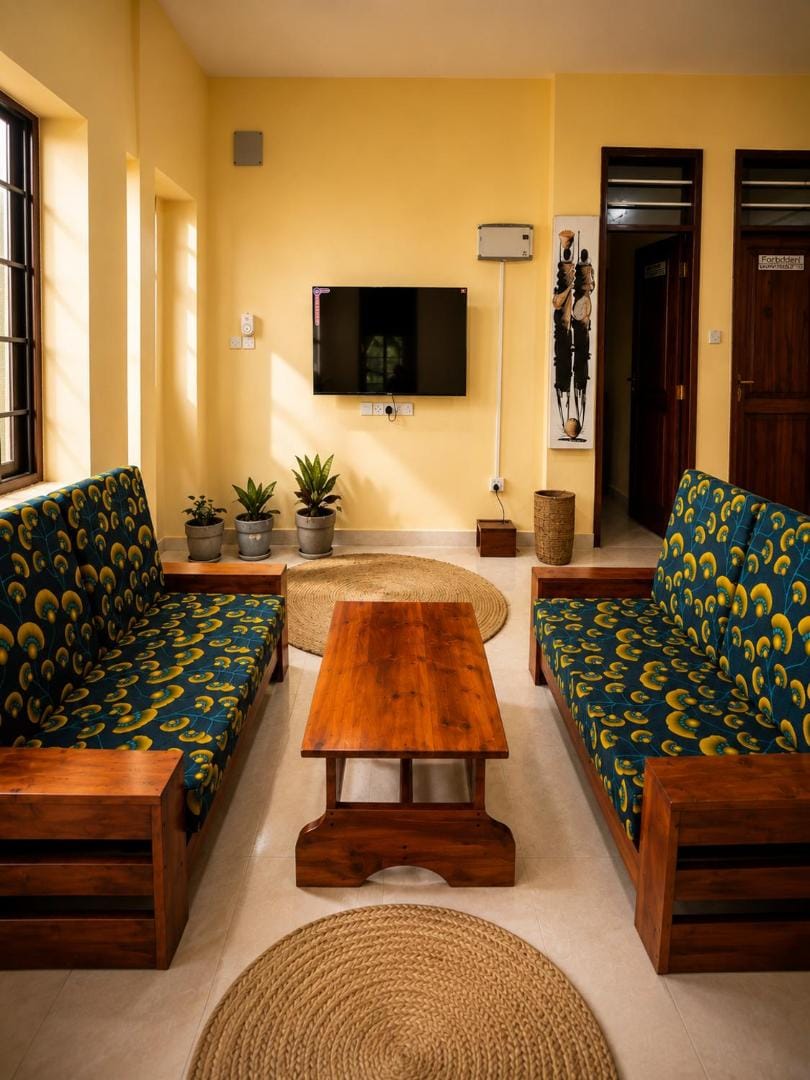 a lounge with teak sofas and bold kitenge cushions
