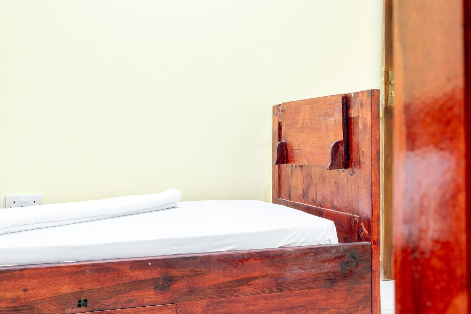 a solid teak bed against a warm painted wall